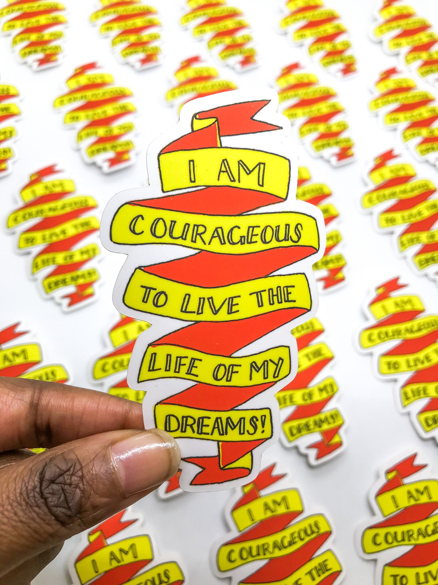 Yellow and red motivational sticker reads, "I AM COURAGEOUS TO LIVE THE LIFE OF MY DREAMS!"