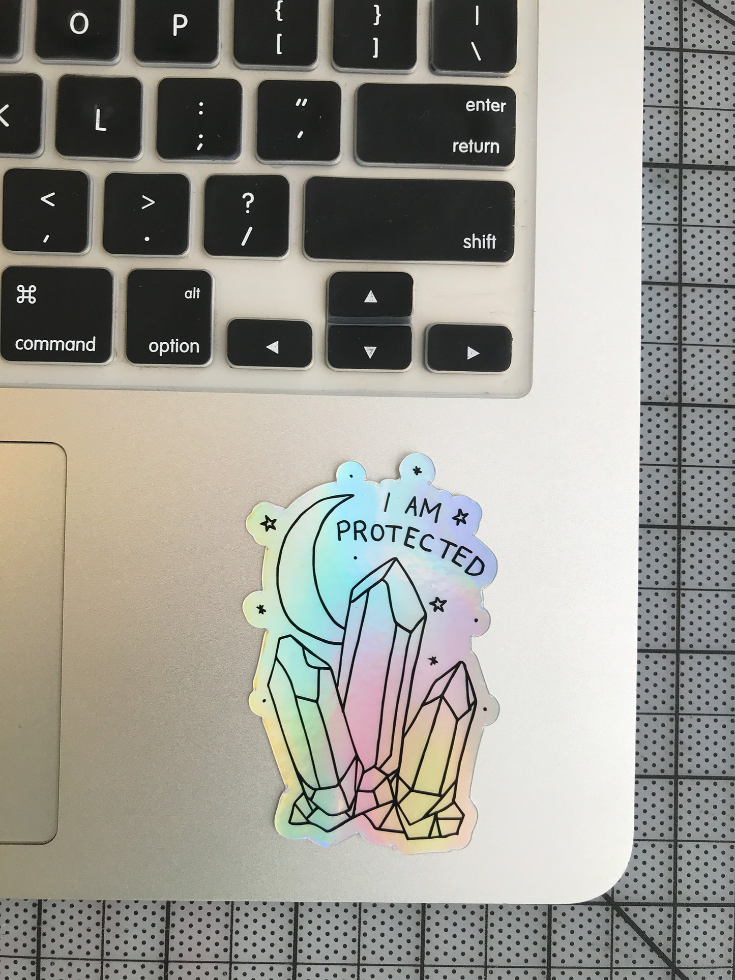 "I Am Protected" holographic sticker on laptop pad