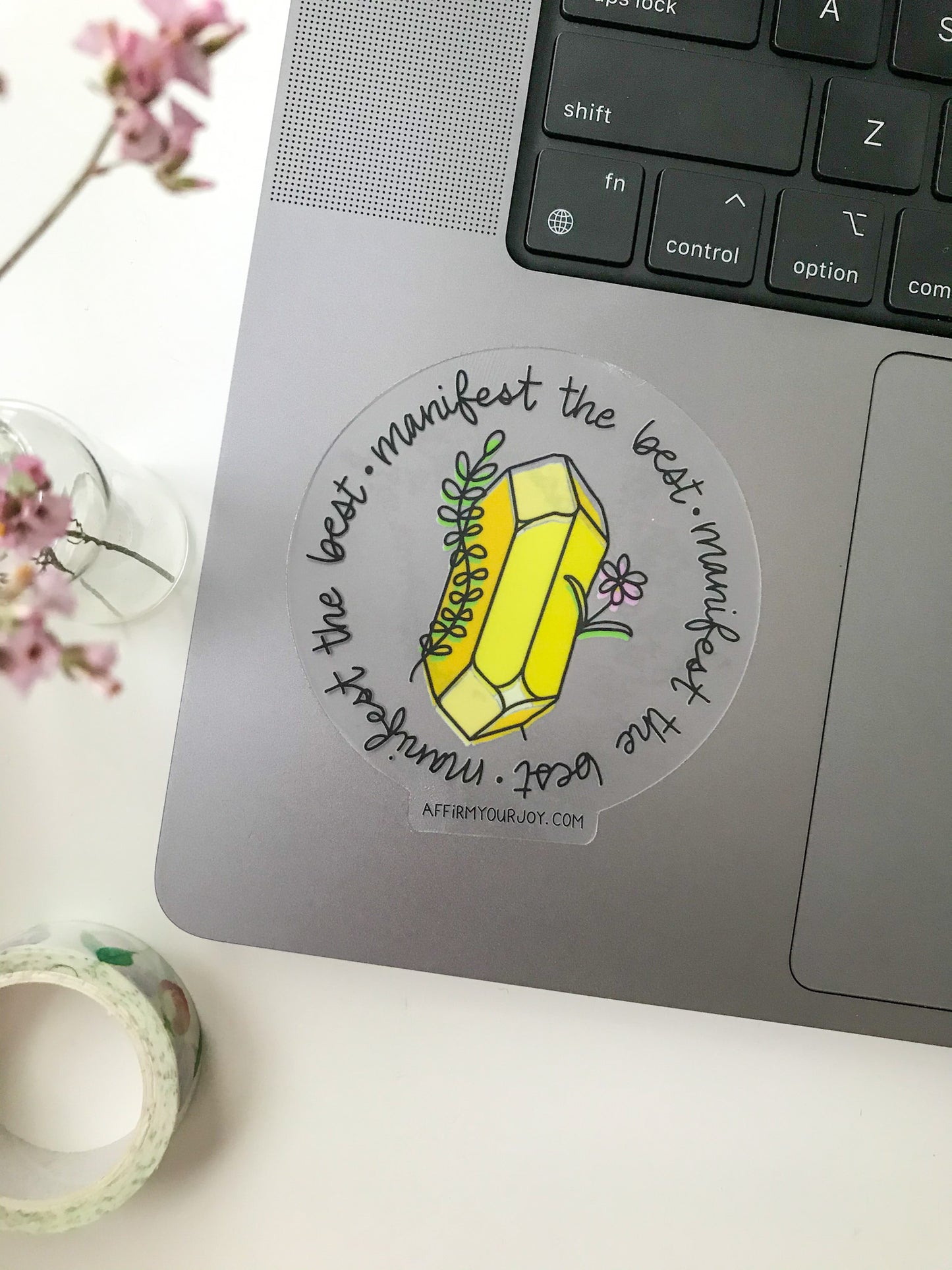 Clear circular sticker with yellow crystal on a laptop