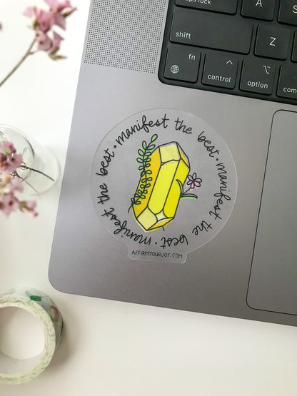 Clear circular sticker with yellow crystal on a laptop
